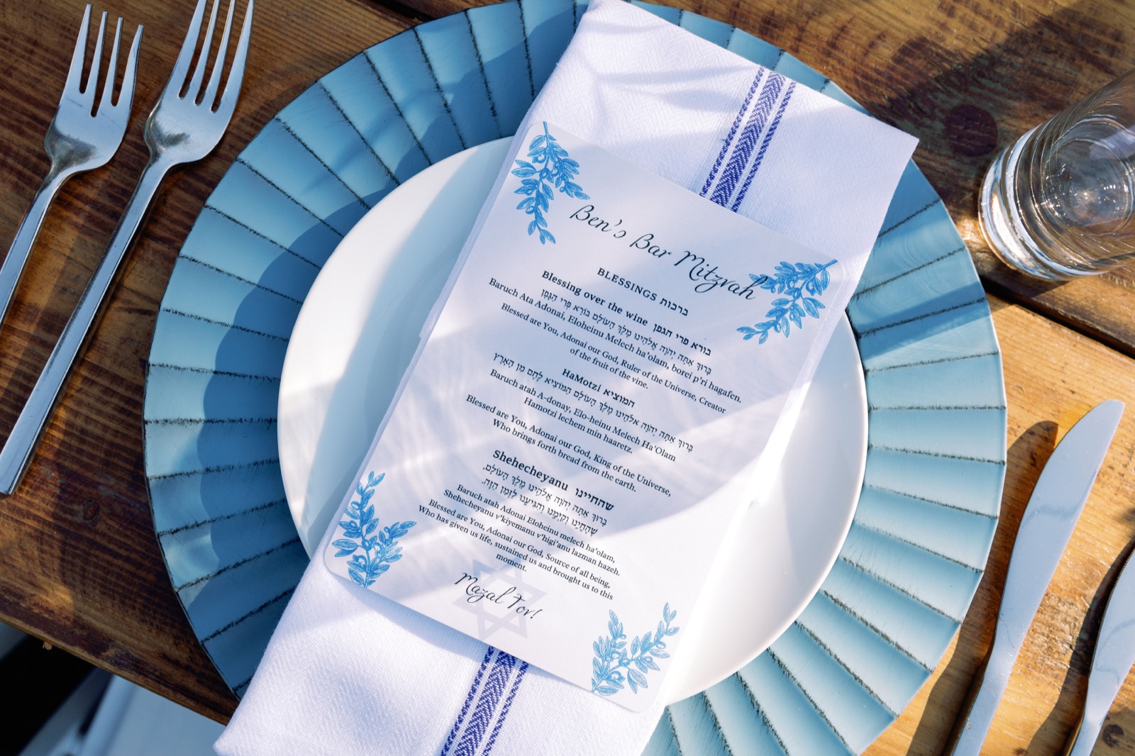 Custom Hebrew and English bar mitzvah blessing card on a blue plate with two forks