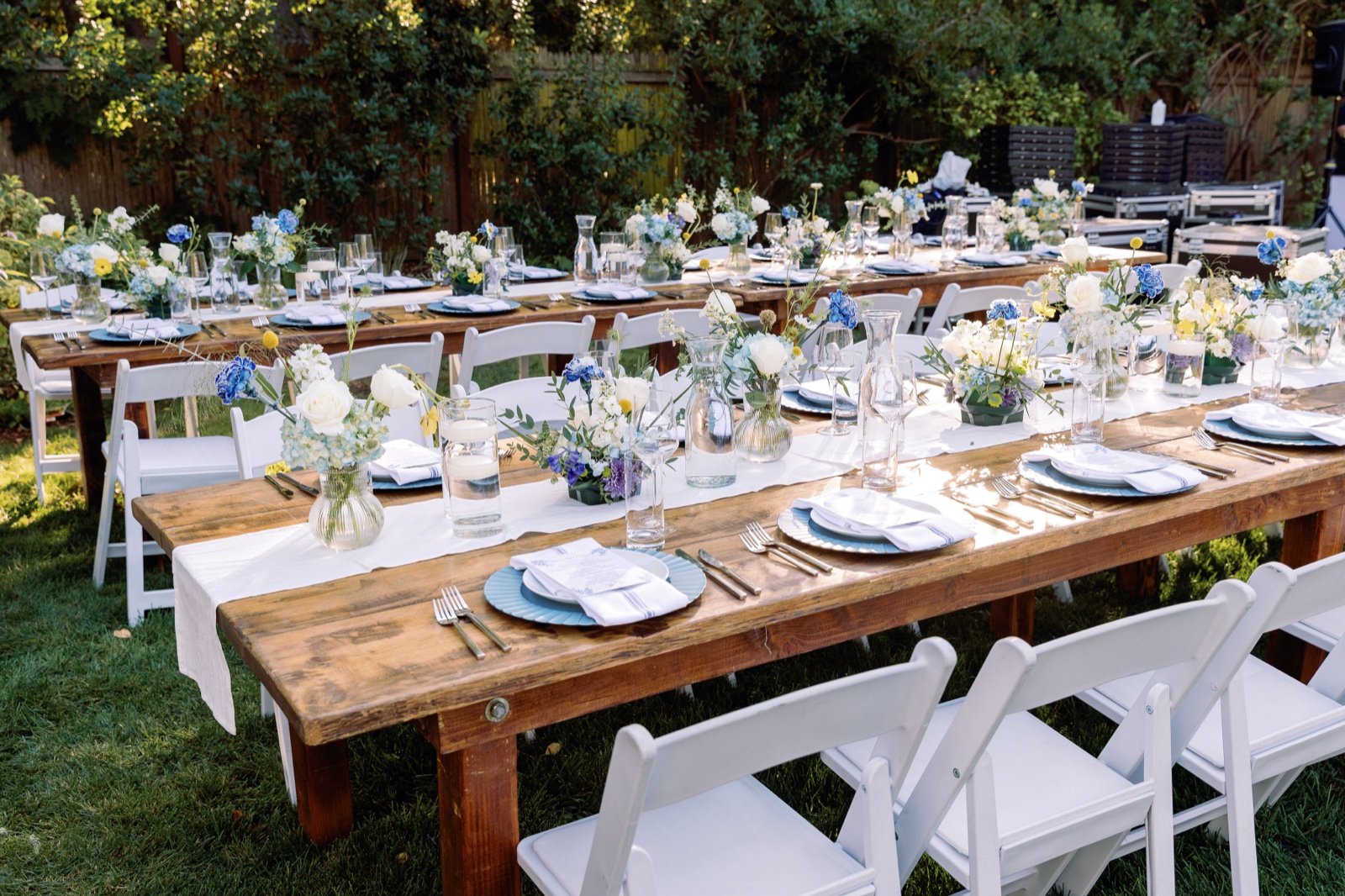 Wide view of long bar mitzvah dinner tables with blue and white florals and white folding chairs