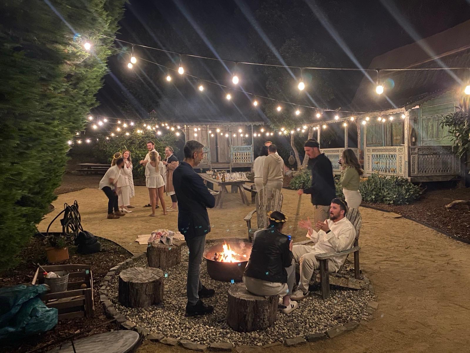 Team gathered around a fire pit at night under string lights