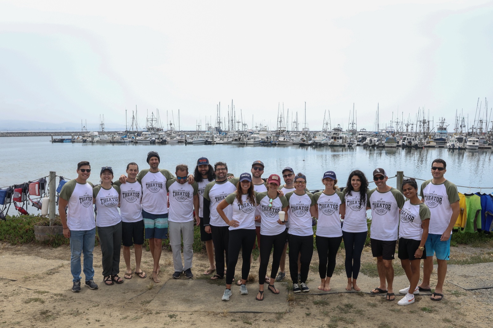 Team in matching shirts posing in front of a marina full of sailboats