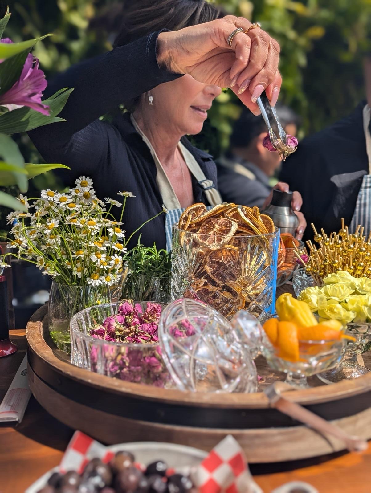 Crystal cocktail station with dried roses, daisies, and a metal shaker mid-pour