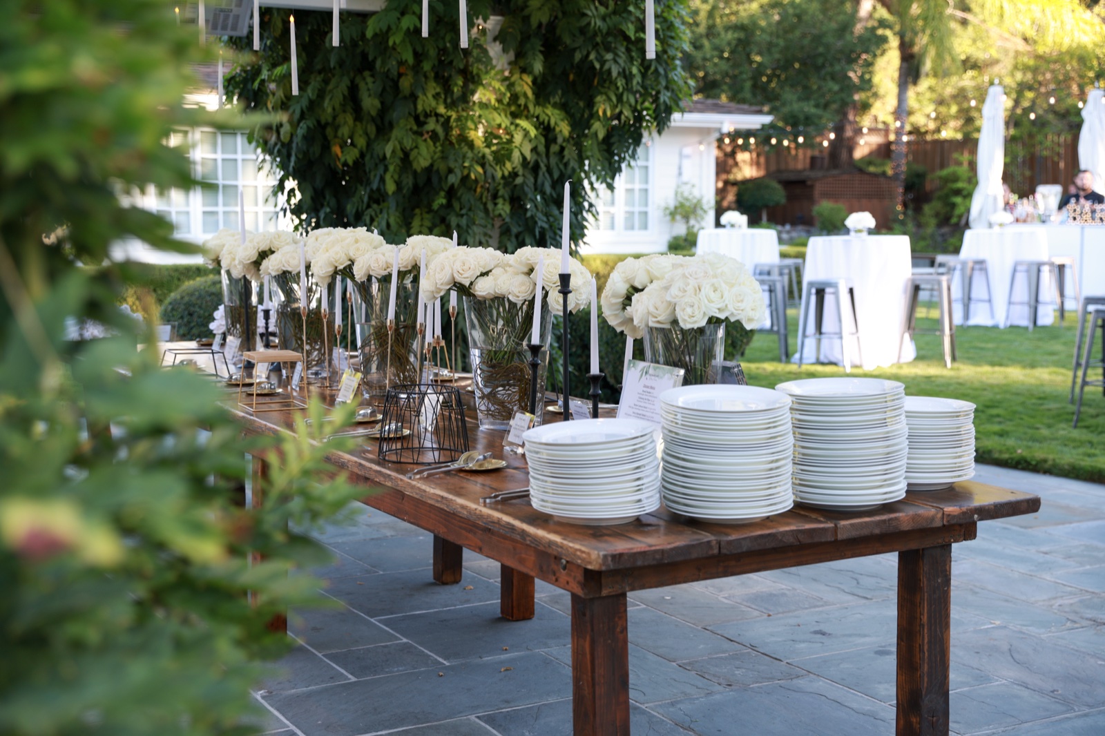 Private dinner setup with white florals and stacked plates on a long wooden table