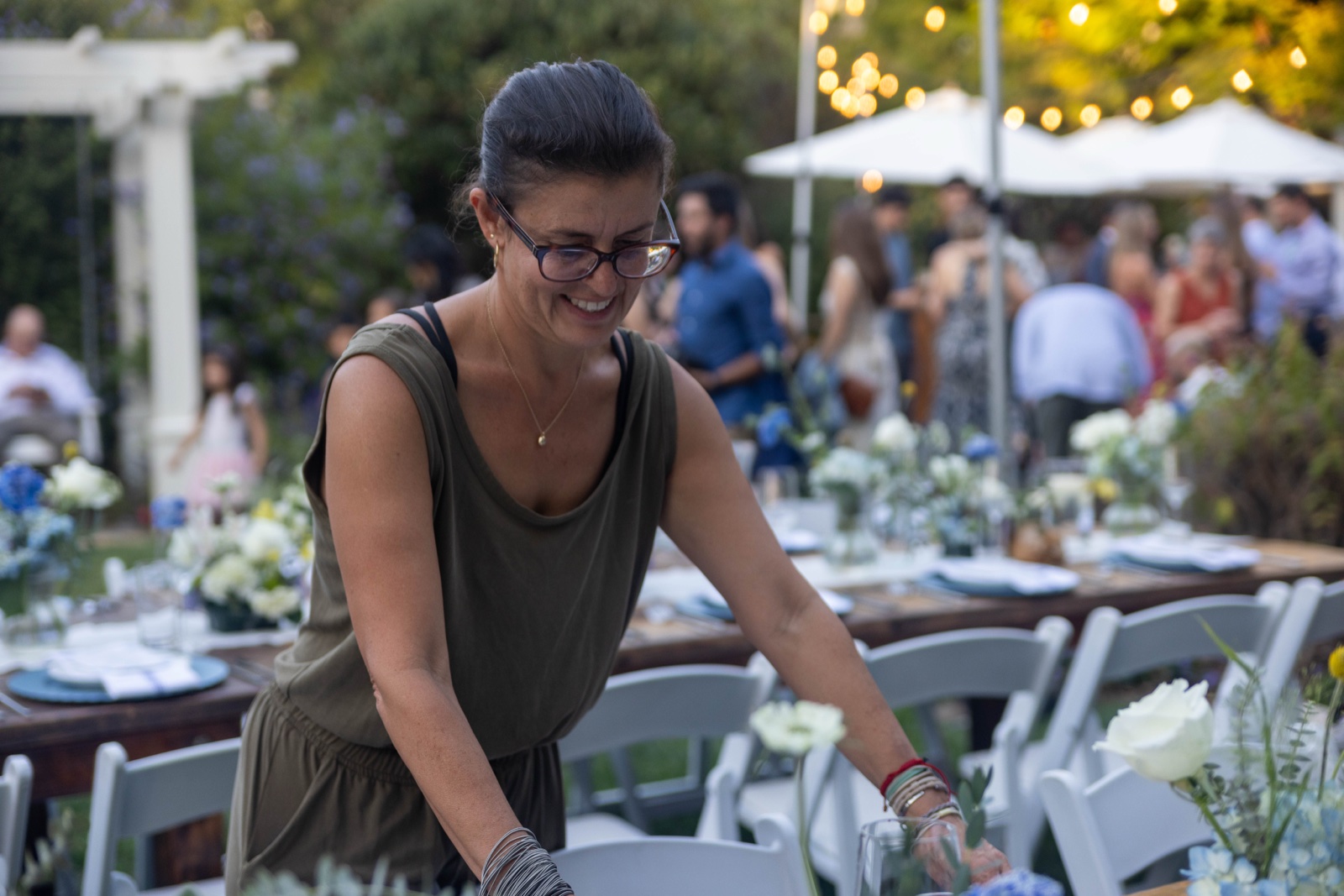 Yakira smiling while setting an outdoor dinner table at dusk